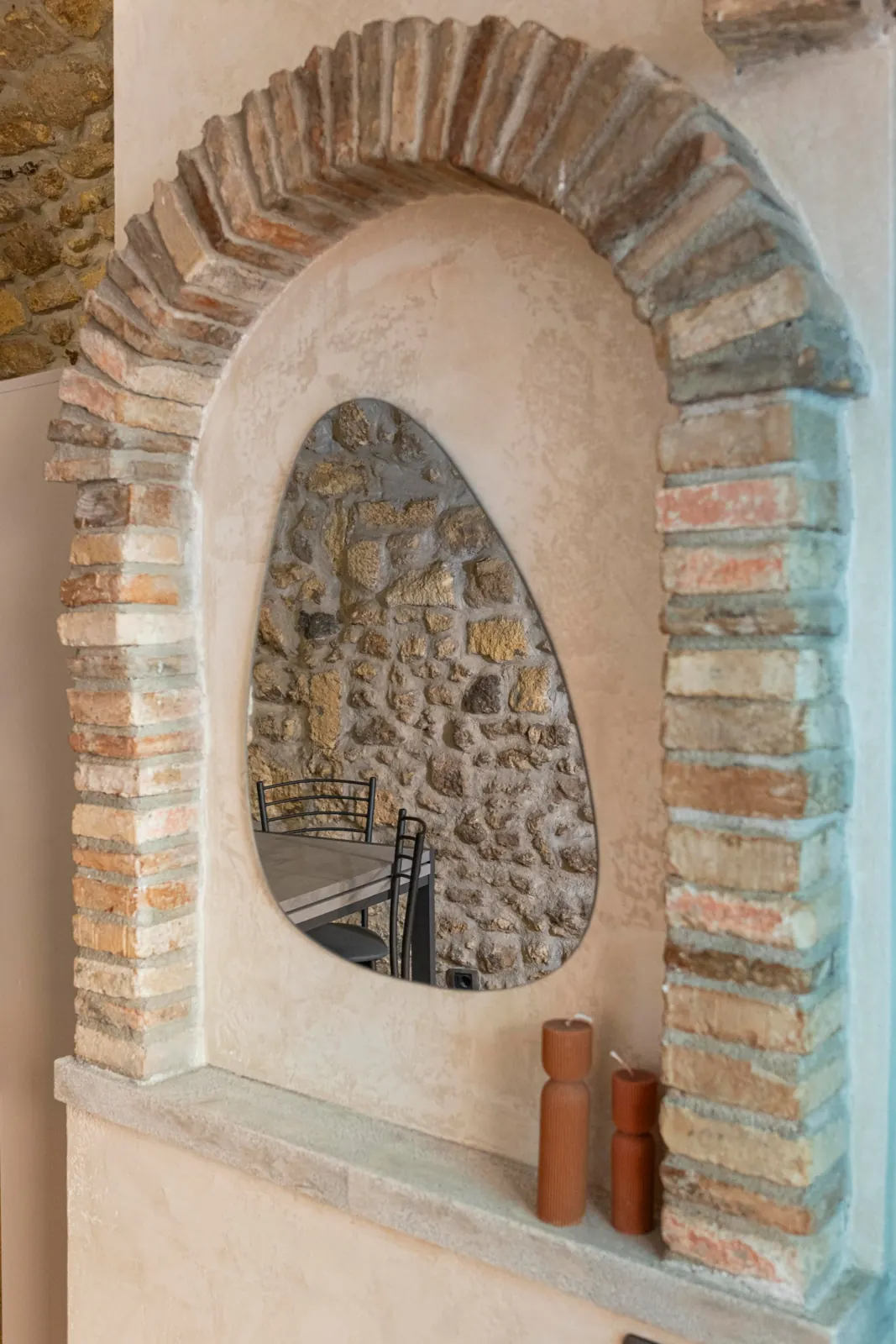 Arco in mattoni e intonaco con specchio che riflette il tavolo e la pietra del loft