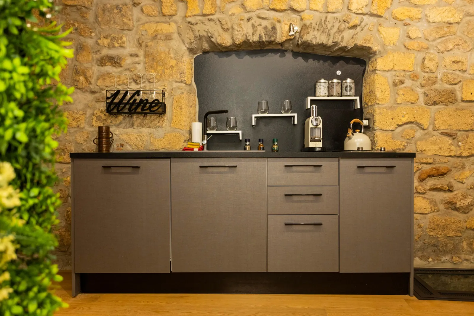 Angolo cucina in una nicchia di pietra: lavello, piano a induzione, macchina Nespresso, bollitore e bicchieri