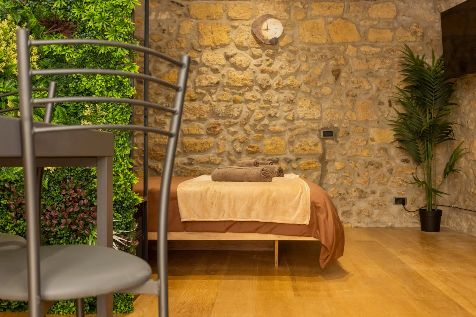 Il letto del loft visto tra le sedie, con asciugamani marroni arrotolati sul plaid