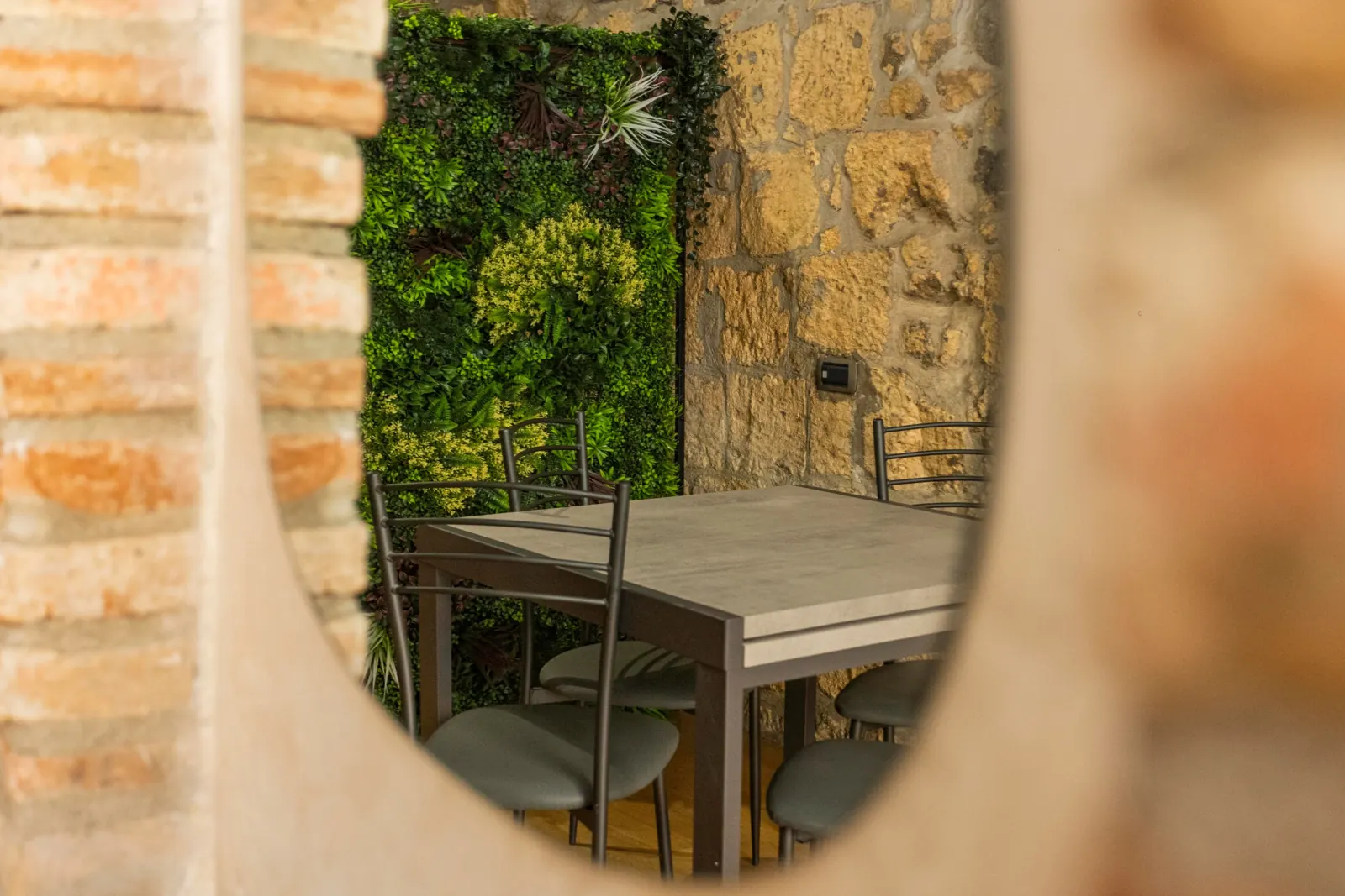 Tavolo e sedie con parete verde, riflessi nello specchio ovale dell'arco in mattoni